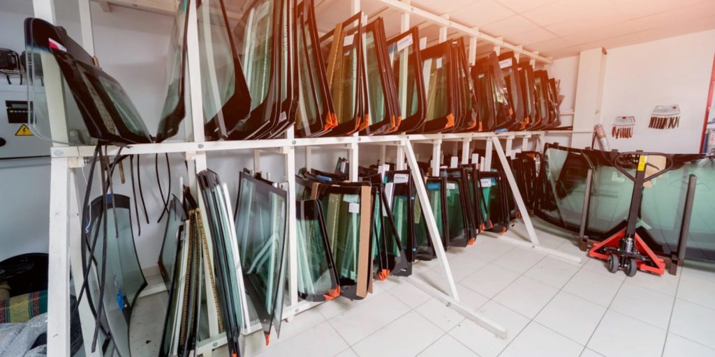 A storage room filled with folded ping pong tables arranged neatly on racks, indicating a facility dedicated to table tennis and auto glass repair.
