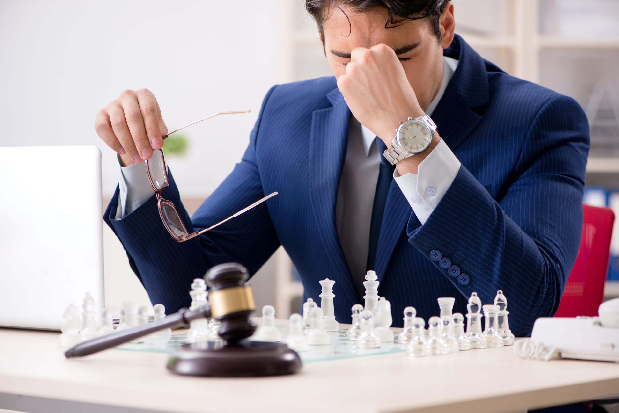 A focused businessman contemplating his next move on an aggressive chessboard, symbolizing strategic representation.