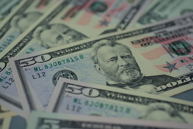 A close-up of scattered U.S. fifty-dollar bills featuring a portrait of Ulysses S. Grant, arranged in various angles with details like serial numbers and security features visible, symbolizing the financial support often associated with personal injury protection claims.