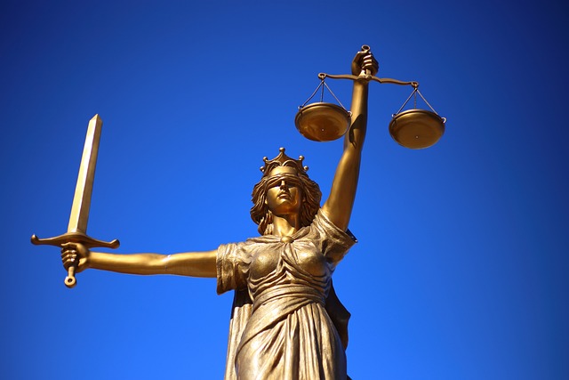 A golden statue of Lady Justice against a clear blue sky. She is blindfolded, holding scales in her right hand and a sword in her left hand, symbolizing fairness and the impartiality of the law, which serves as the foundation for personal injury protection.