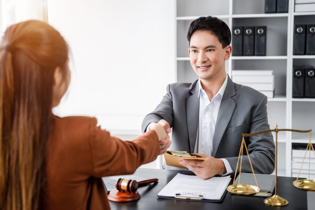 Lawyer shaking hands with client after discussing final contract agreement.