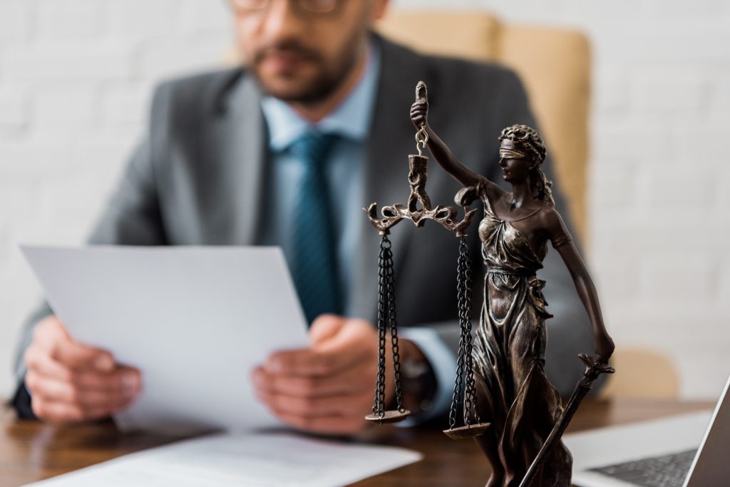 close-up view of lady justice statue and lawyer working working with papers behind